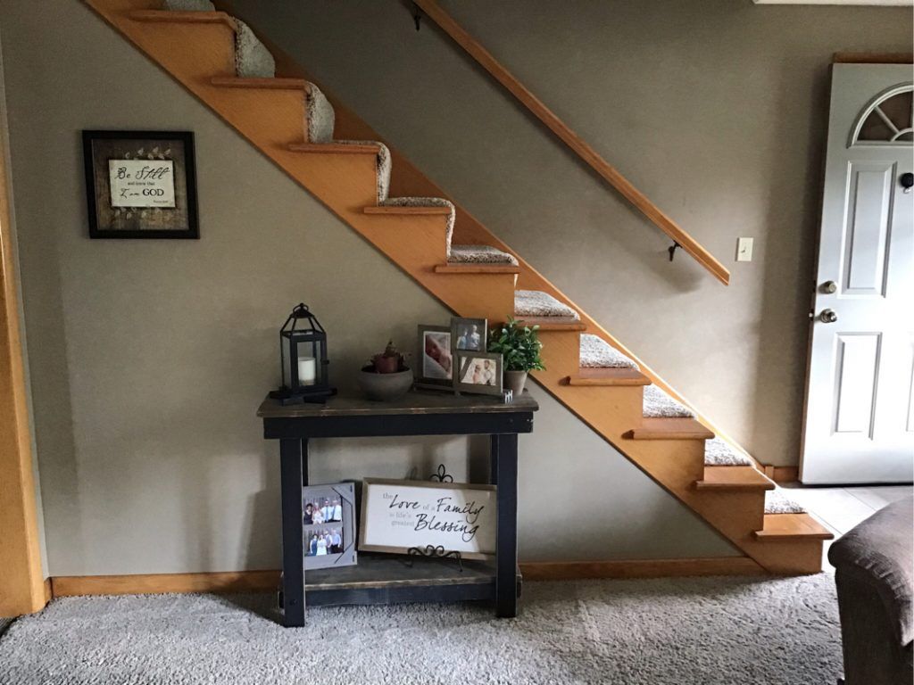 A staircase in a living room with a table underneath it.