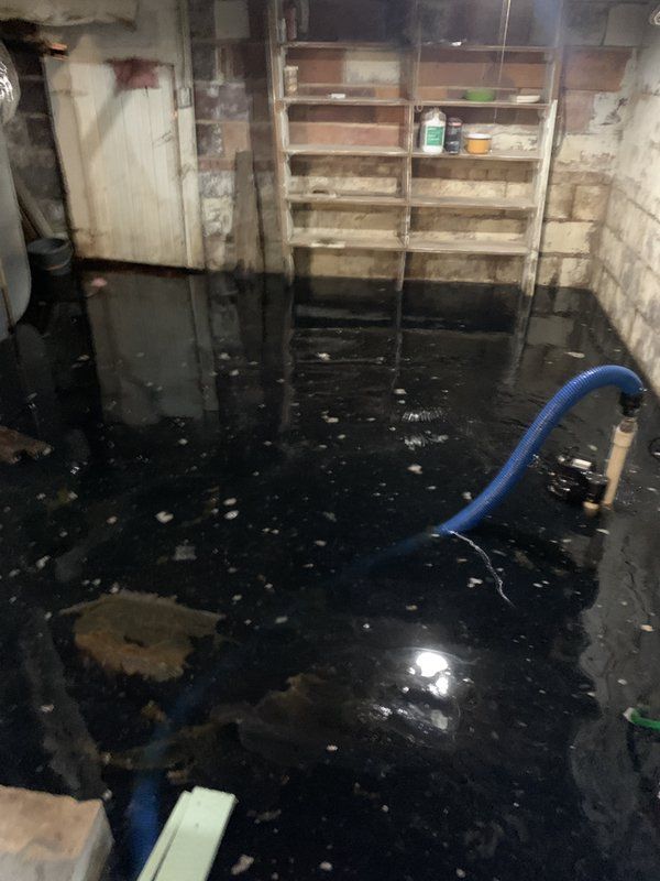 A flooded basement with a blue hose in it