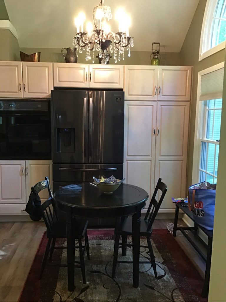 A kitchen with cabinets, table and chairs, and a refrigerator.