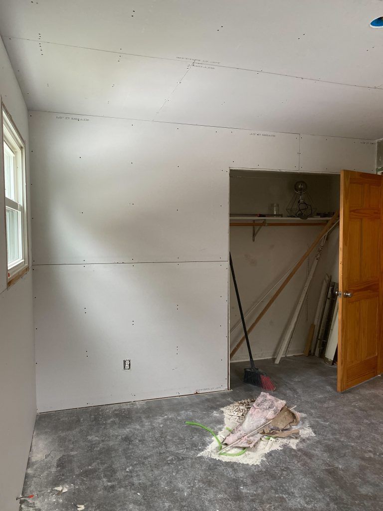 A room with drywall on the walls and a broom on the floor.
