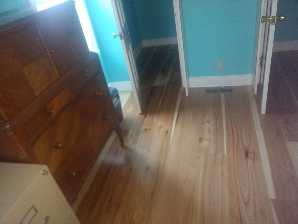 A room with hardwood floors, blue walls, and a wooden dresser.
