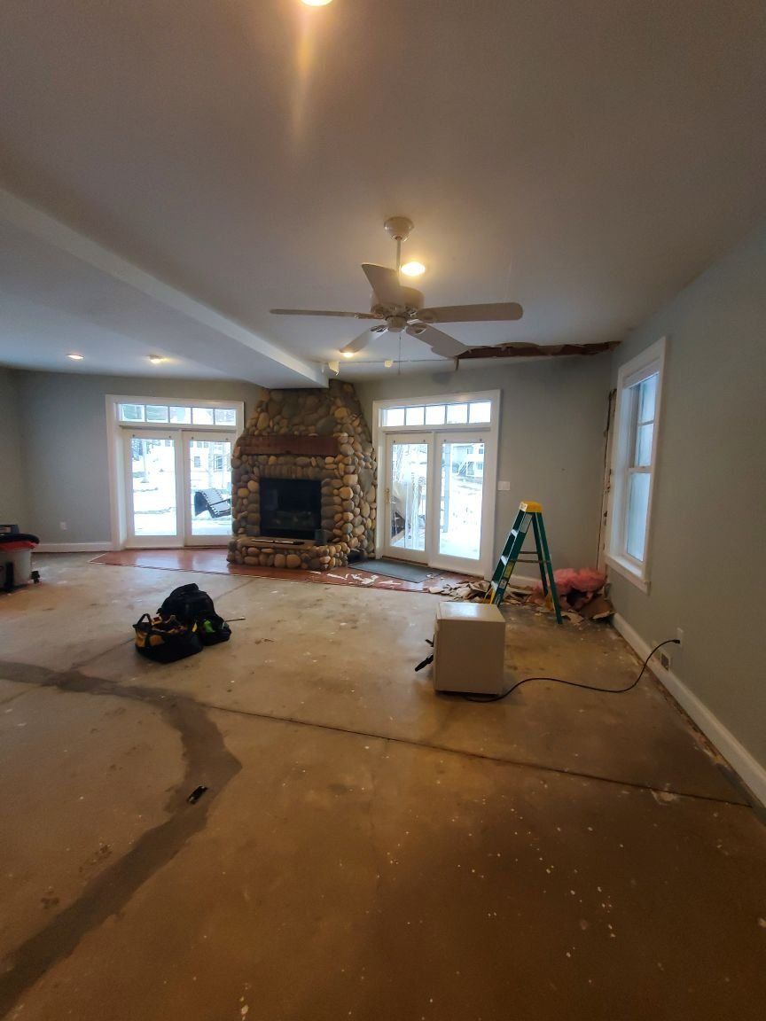 A living room being repaired from water damage with a ladder and fireplace. 