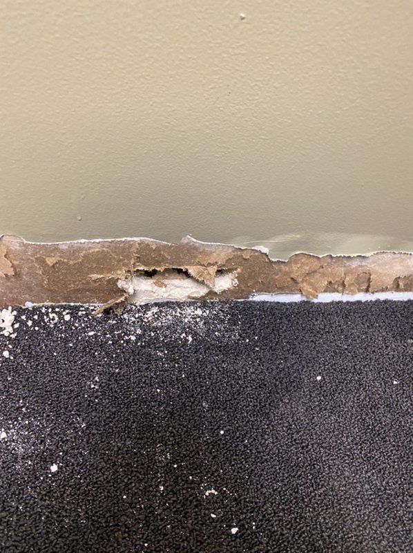 A close up of a wall with water damage and a hole in it.