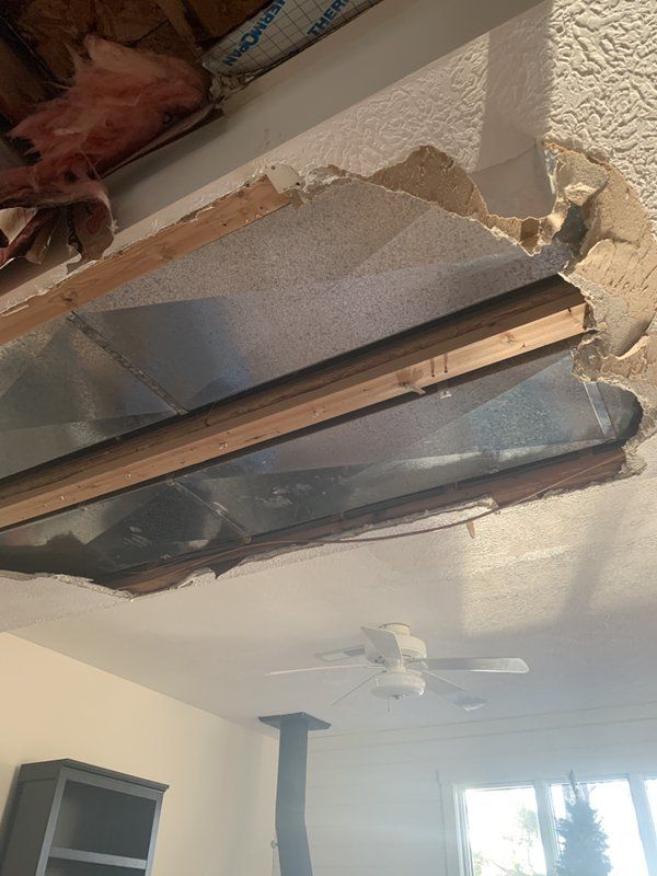 A damaged room with a hole in the ceiling and a ceiling fan.