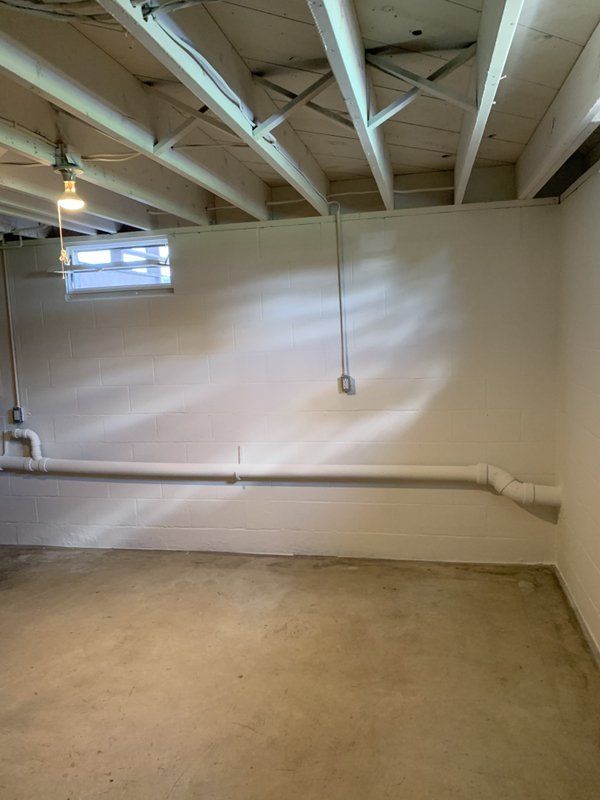 An empty basement with a ceiling and a window.