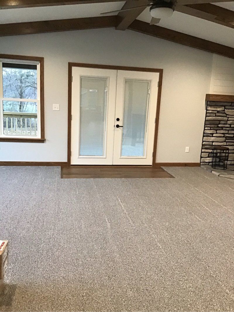 An empty living room with a fireplace and sliding glass doors.