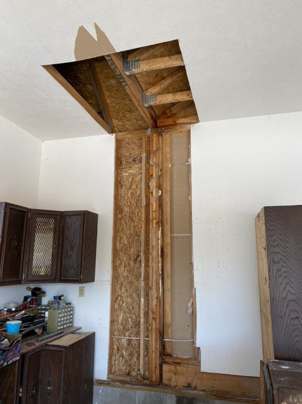 A kitchen with a hole in the ceiling and wooden cabinets.