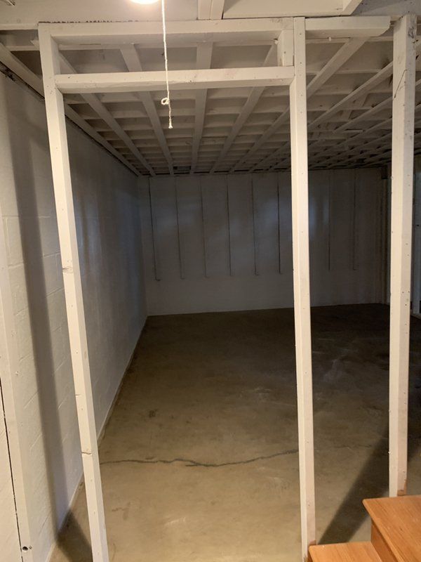 An empty basement with white walls and a ceiling.