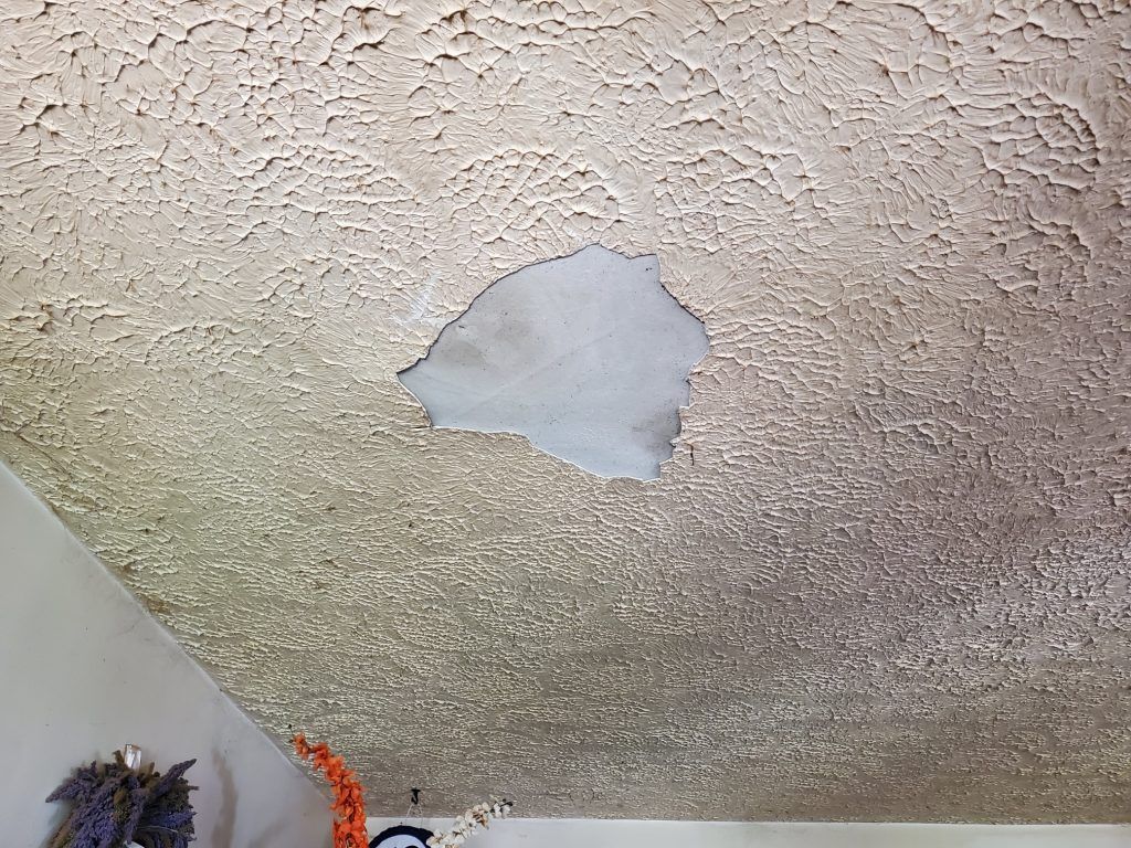 A ceiling with roof damage and hole in ceiling.