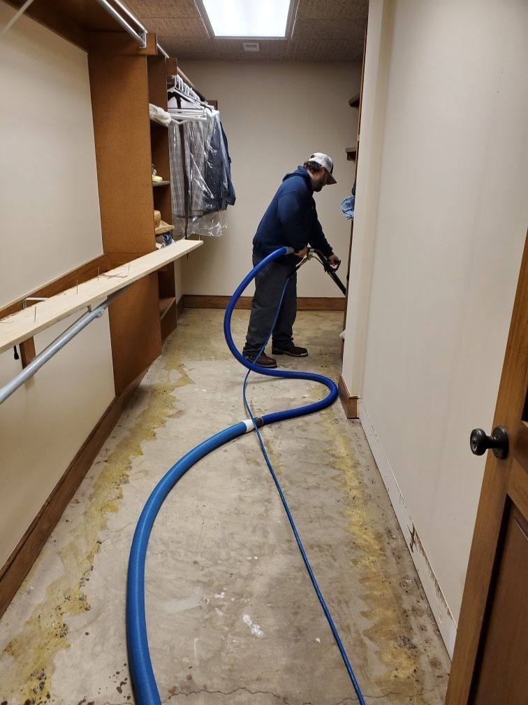 A man is using an industrial vacuum cleaner to clean a closet.