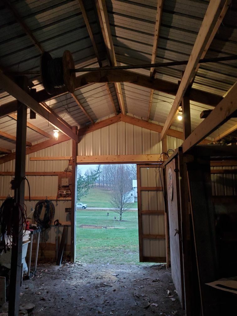 The inside of a barn with the door open to a field.
