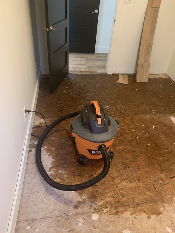 An industrial vacuum cleaner is sitting on the floor in a room.