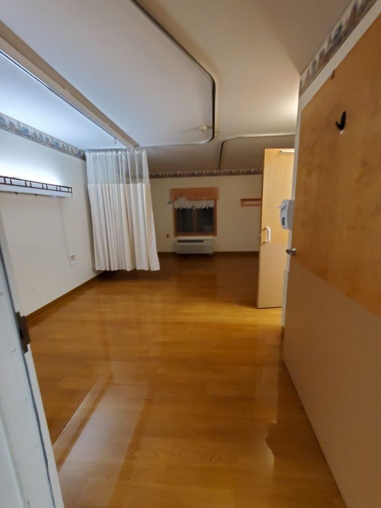 A room with a wooden floor and a white curtain hanging from the ceiling.