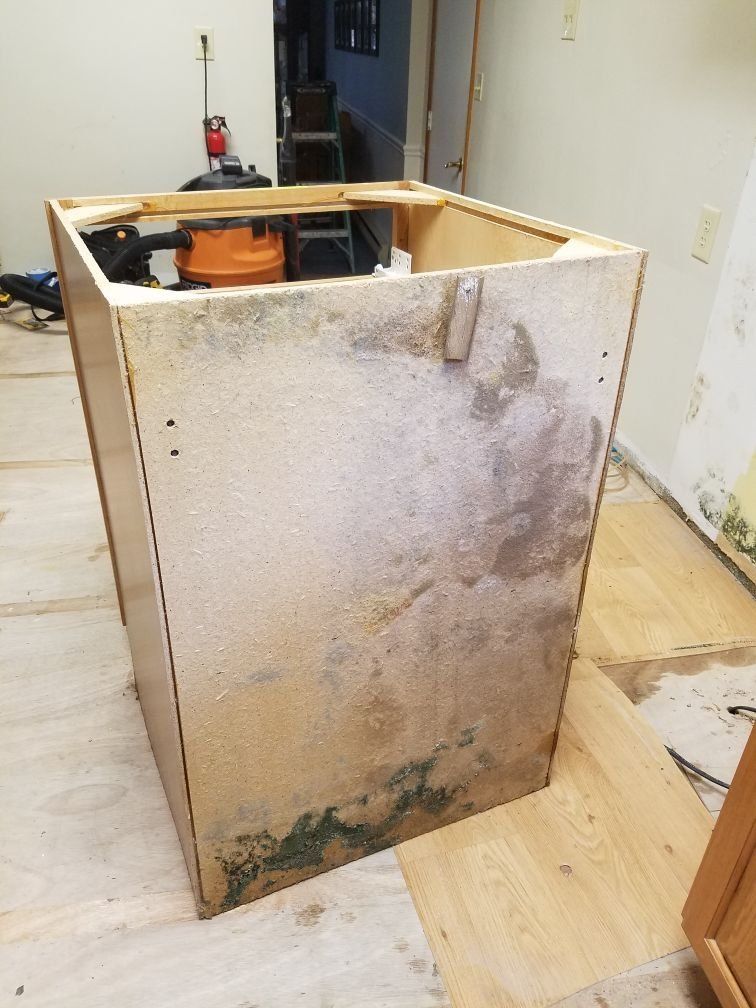 A water damaged cabinet sitting on the floor.