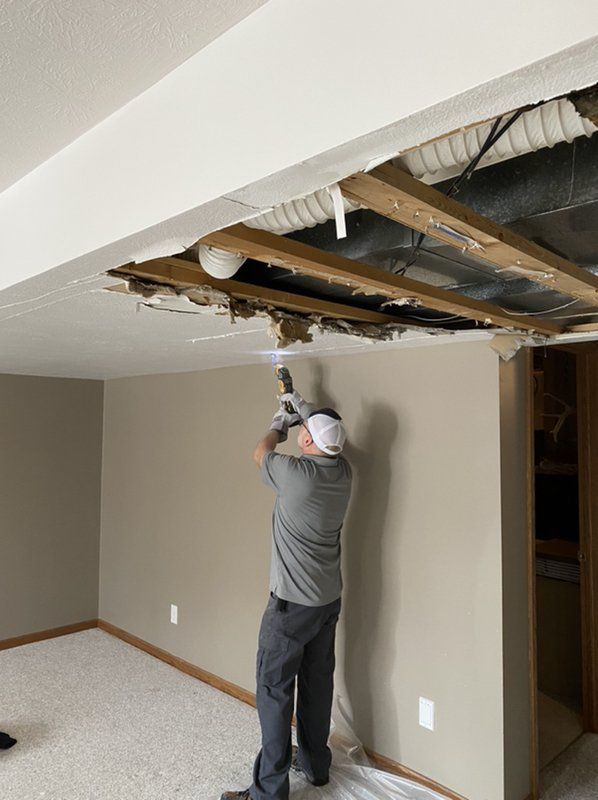 A man is repairing the damaged ceiling of a basement.