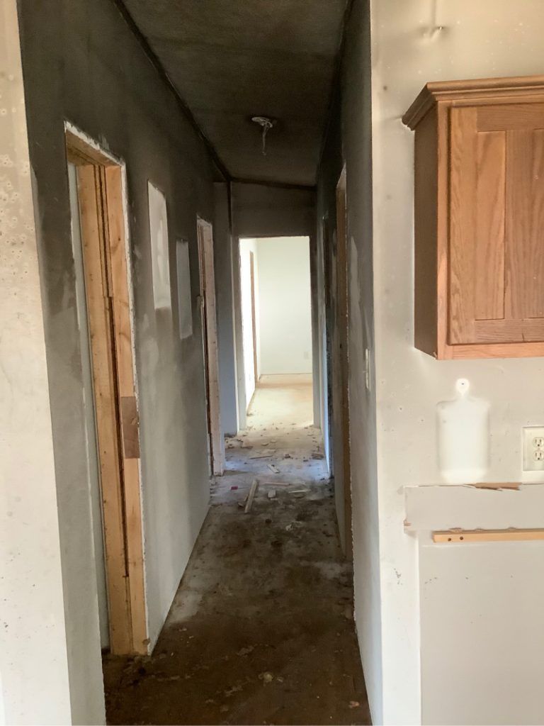 A long hallway with smoke and fire damage.