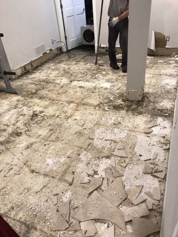 A man is standing on a dirty floor in a room.