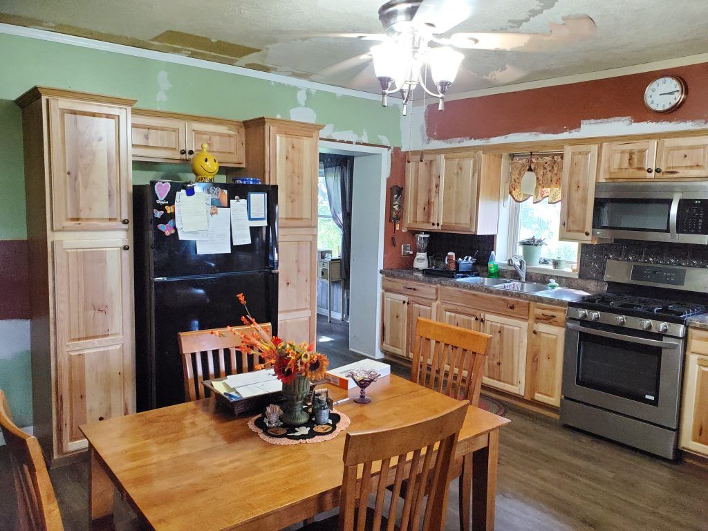 A kitchen with a table and chairs, a refrigerator, stove, microwave and appliances. 