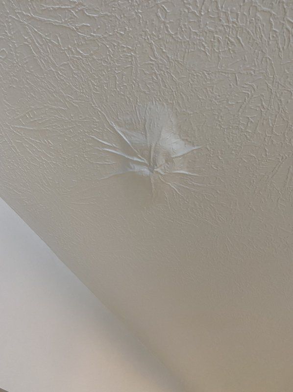A close up of a damaged ceiling with a hole in it.