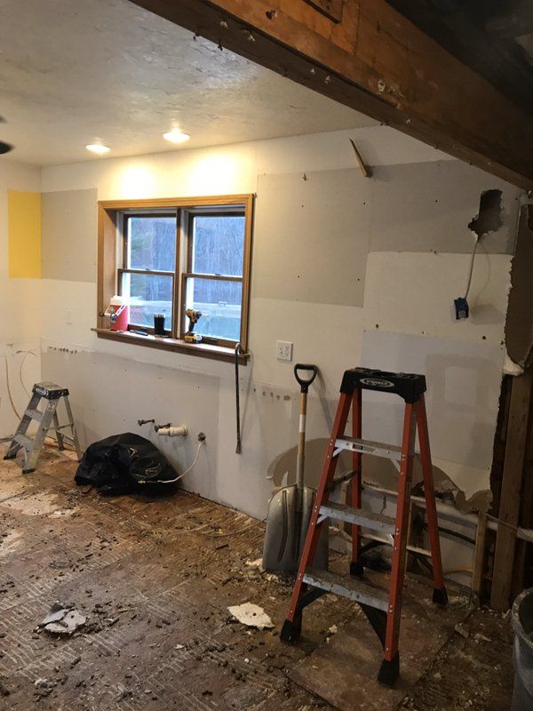 A room being repaired from water damage with tools, ladders, and  a window.