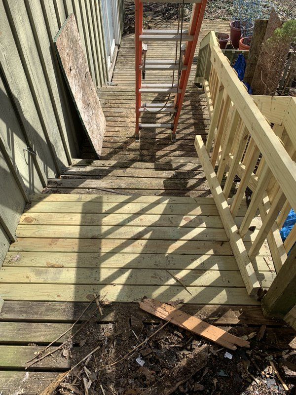 A wooden deck with stairs and a ladder in the background.