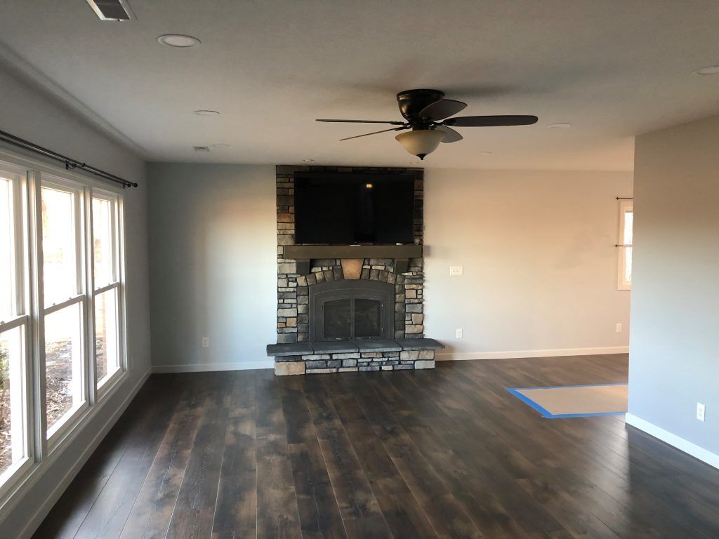 An living room with wood floors, a fireplace, and a ceiling fan.