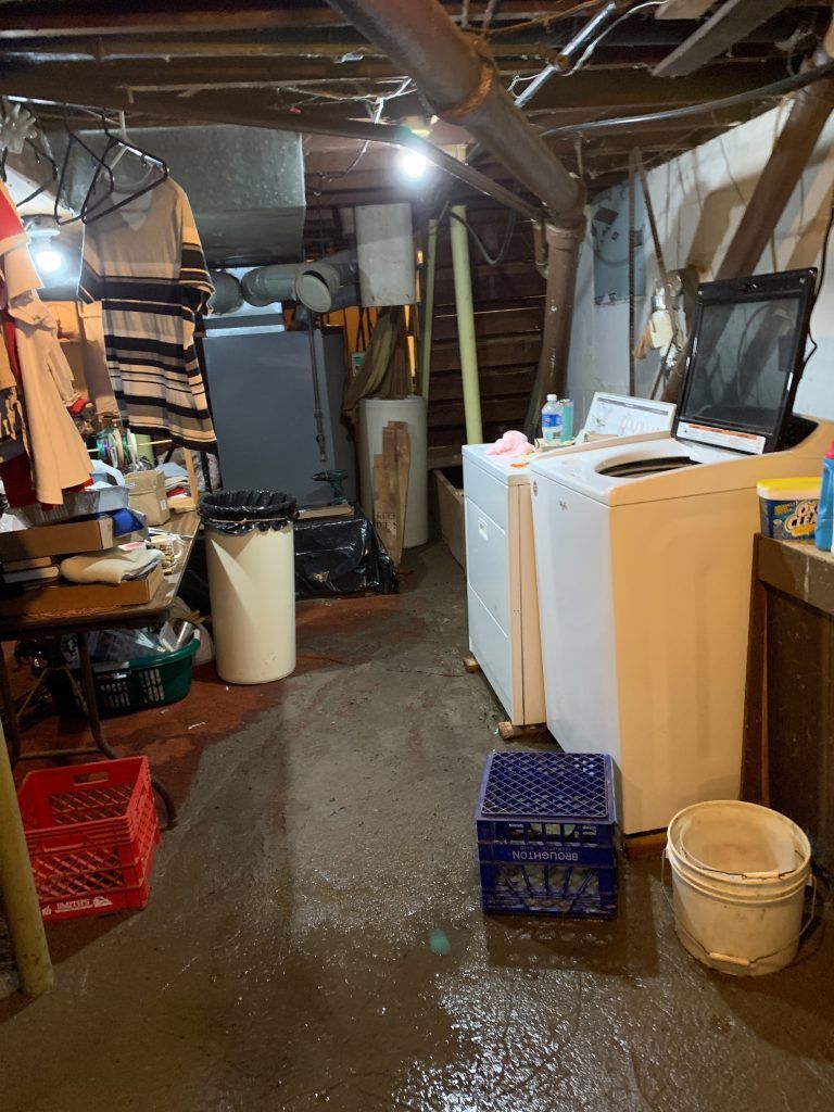 A dirty basement with a washer and dryer in it.