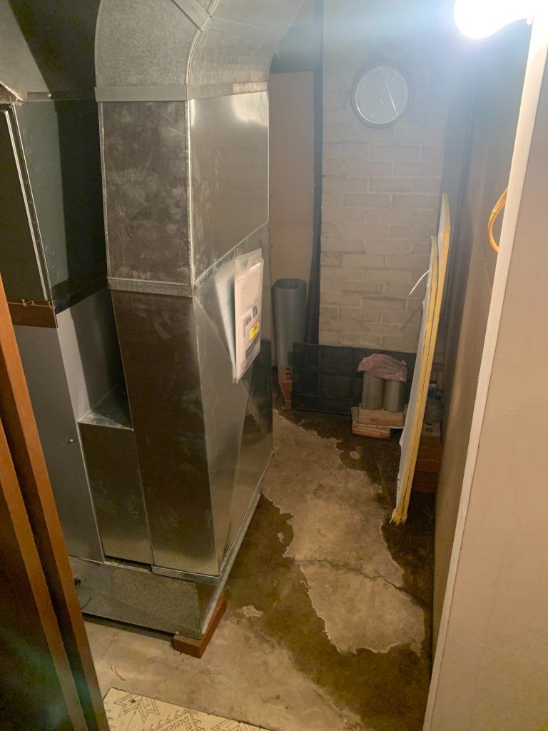 A room with a clock on the wall and a drain on the floor.