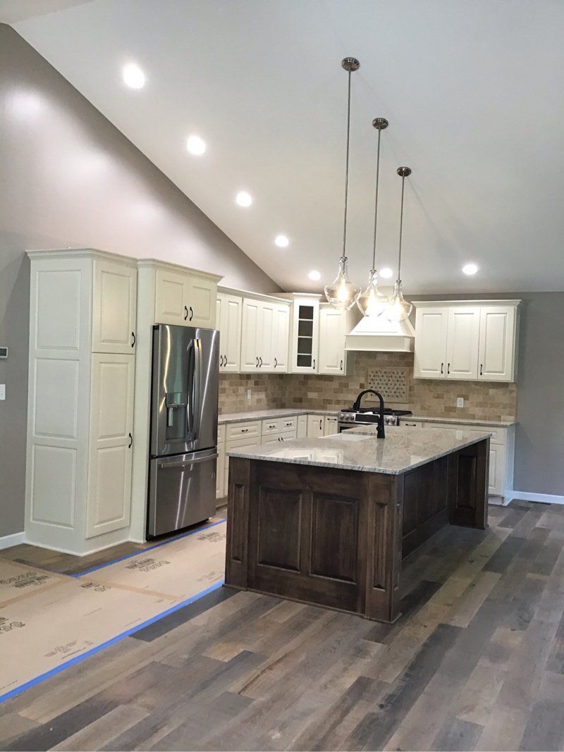 A kitchen with white cabinets , stainless steel appliances , and a large island.