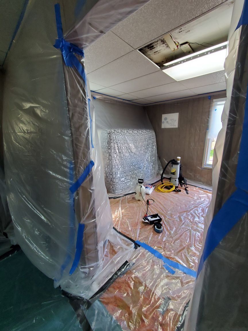 A room is covered in plastic and has industrial tools on the floor. 