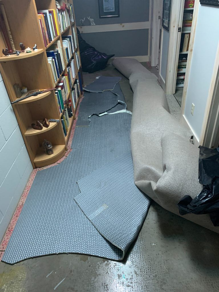 A carpet is laying on the floor in a room next to a bookshelf.