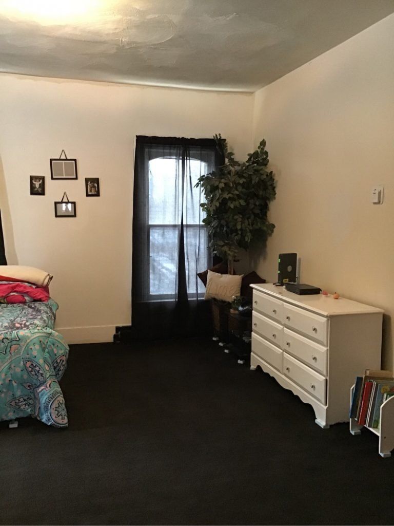 A bedroom with a bed , dresser , and window.