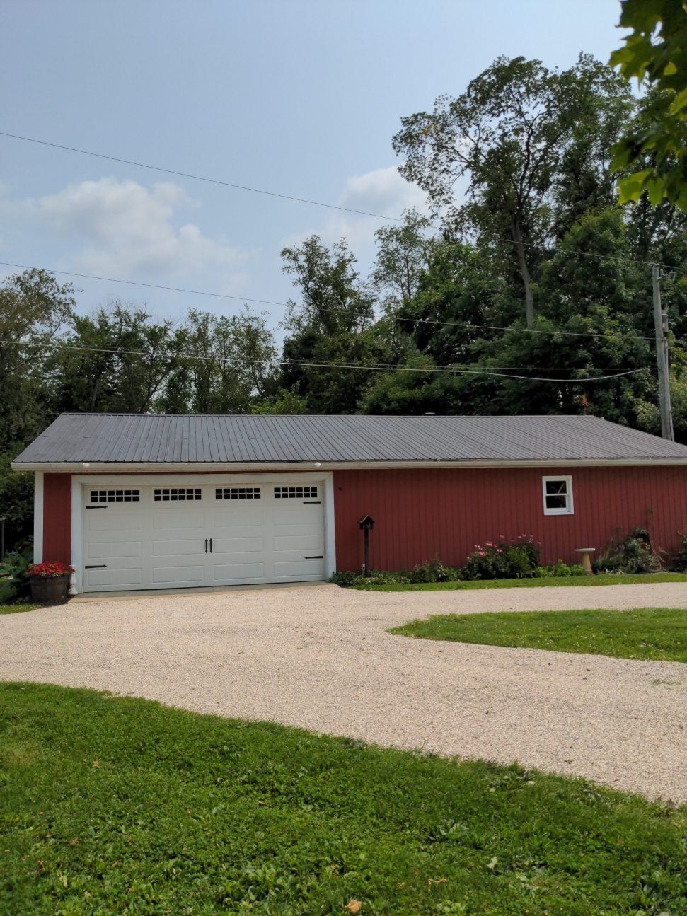 A red garage with a white door and a gravel driveway