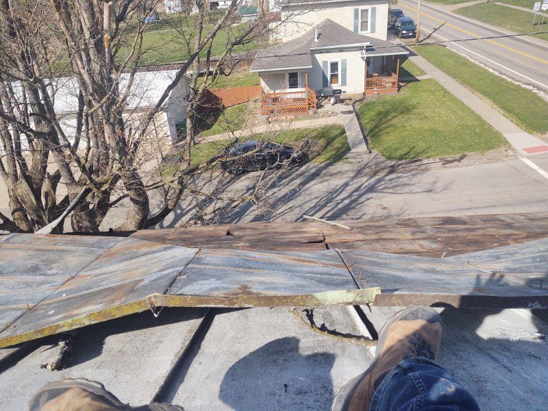 A person is standing on top of a roof looking down at a street.