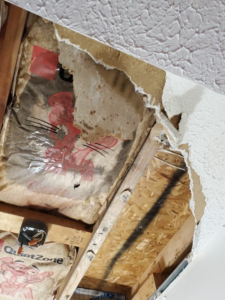 A close up of a damaged ceiling with a hole in it.