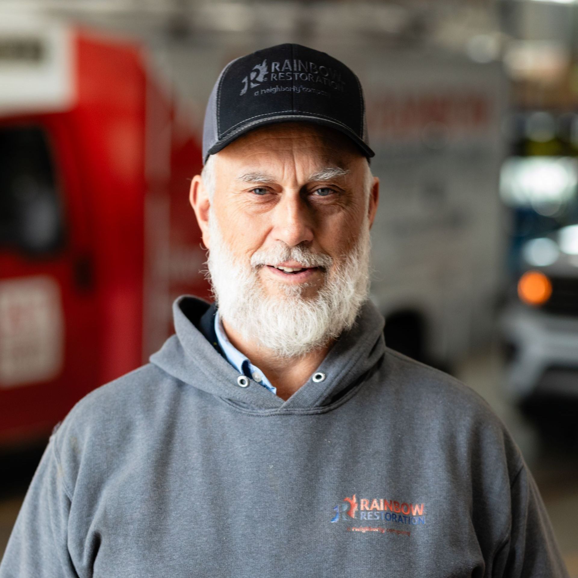 A man with a beard is wearing a hat and a hoodie.