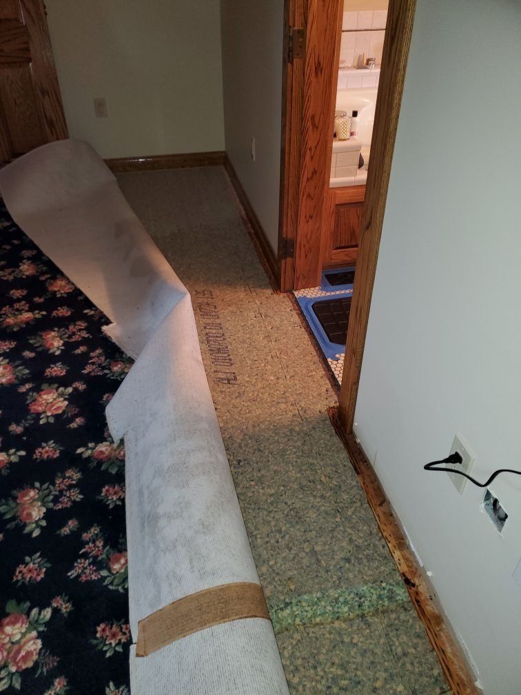 A roll of carpet is sitting on the floor in a room next to a door.