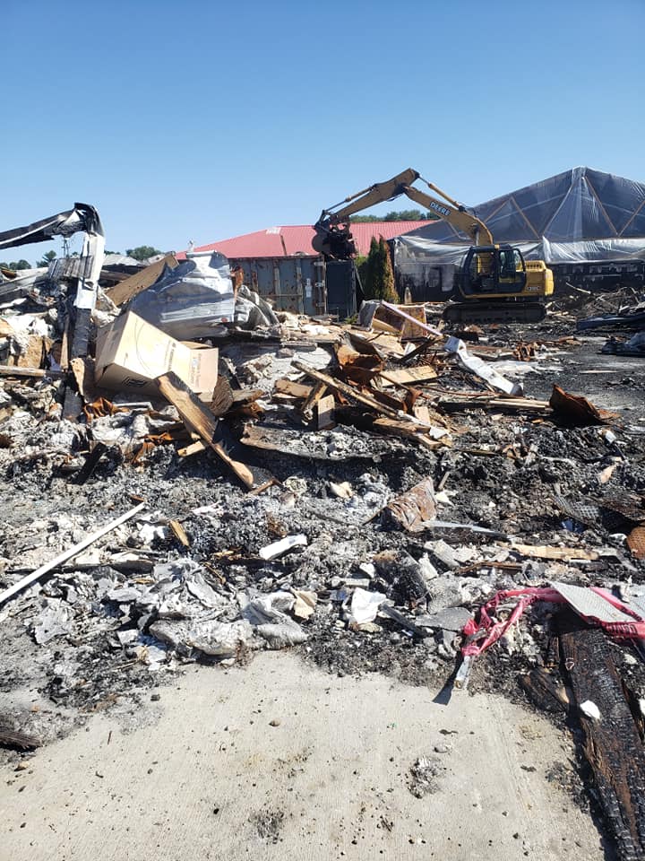 A large pile of rubble is being demolished with a bulldozer in the background.