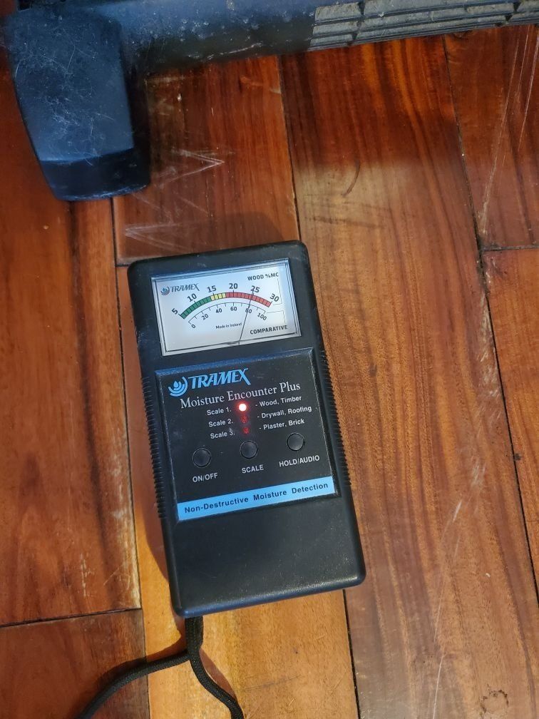 A moisture meter is on a wooden floor.