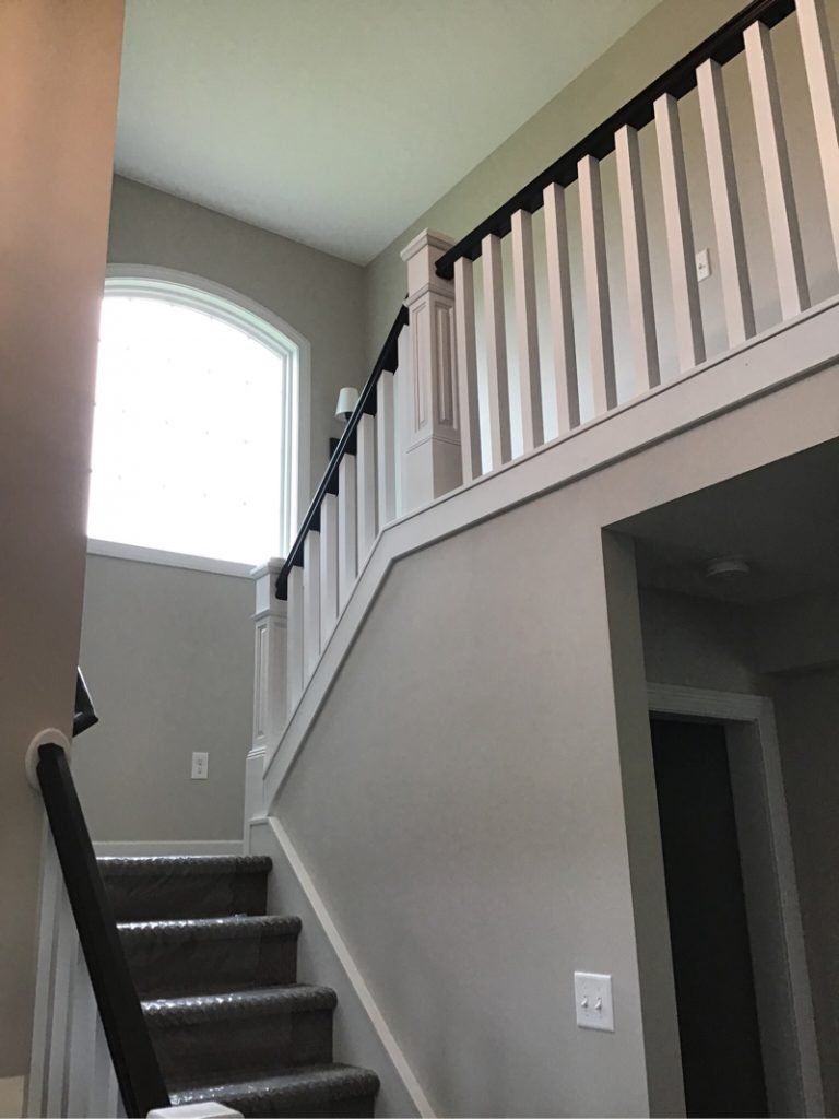 A staircase of a house with a white railing and a window