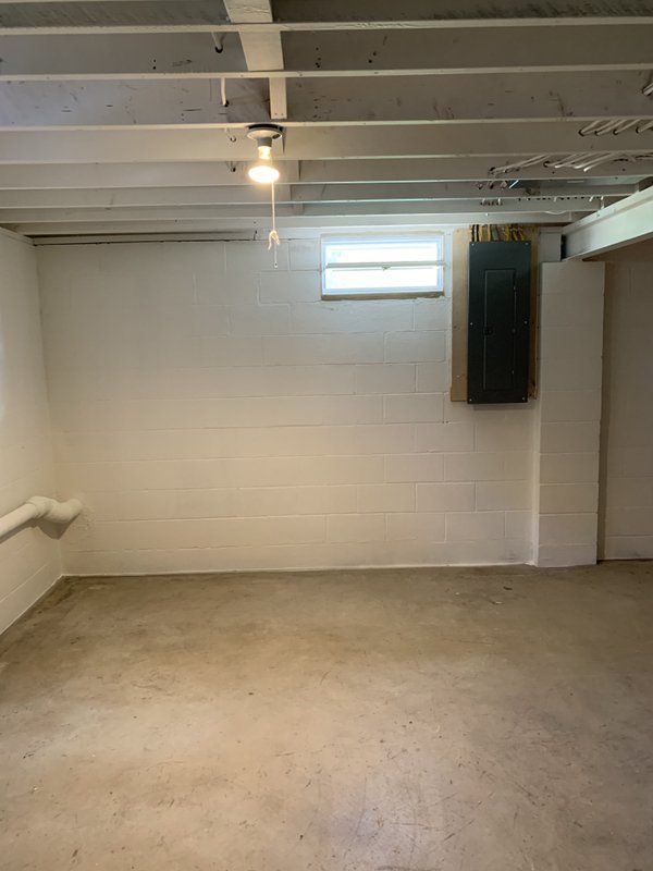 An empty basement with white brick walls and a concrete floor.