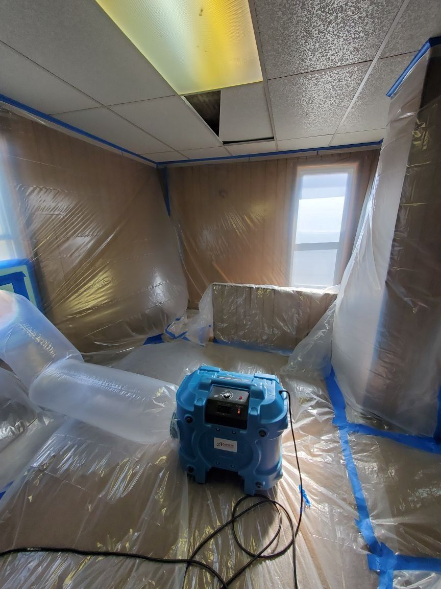 A room is covered in plastic and a vacuum cleaner is sitting on the floor.