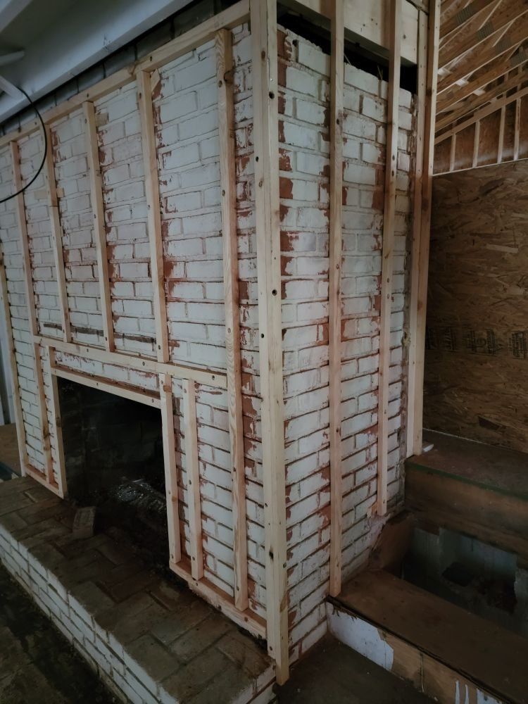 A brick fireplace is being built in a house.