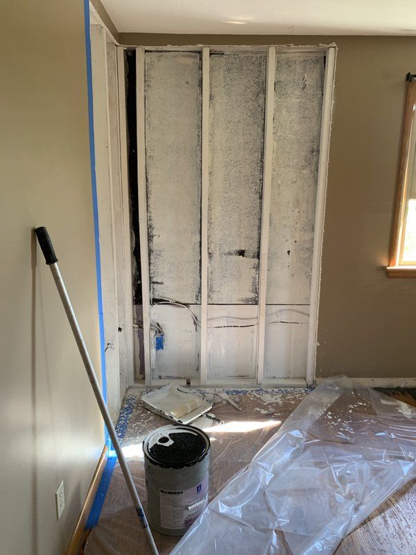 A fire damaged basement with a bucket of paint and a mop on the floor.