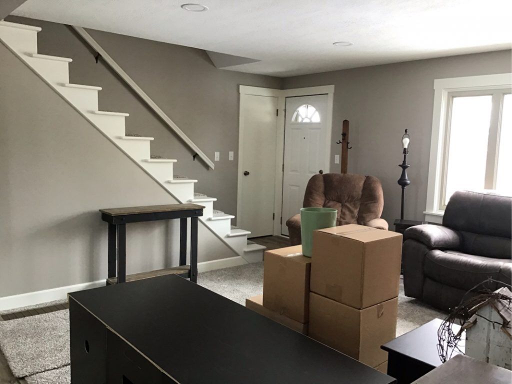 A living room with a staircase and boxes on the floor.