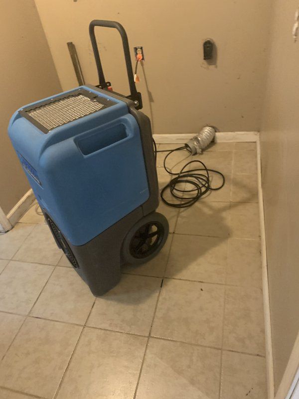 A blue and black machine is sitting on a tiled floor in a room.