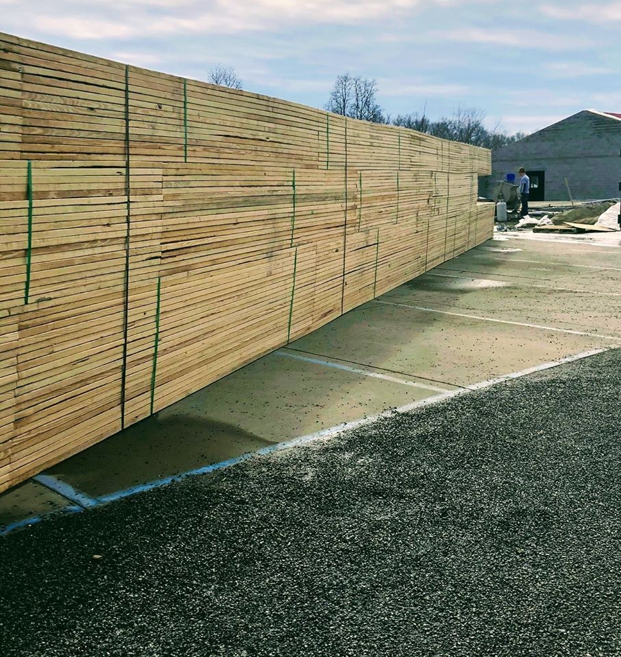 A large wooden fence is sitting on top of a gravel road.