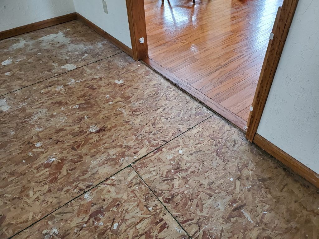 A room with a wooden floor and a doorway leading to a dining room.
