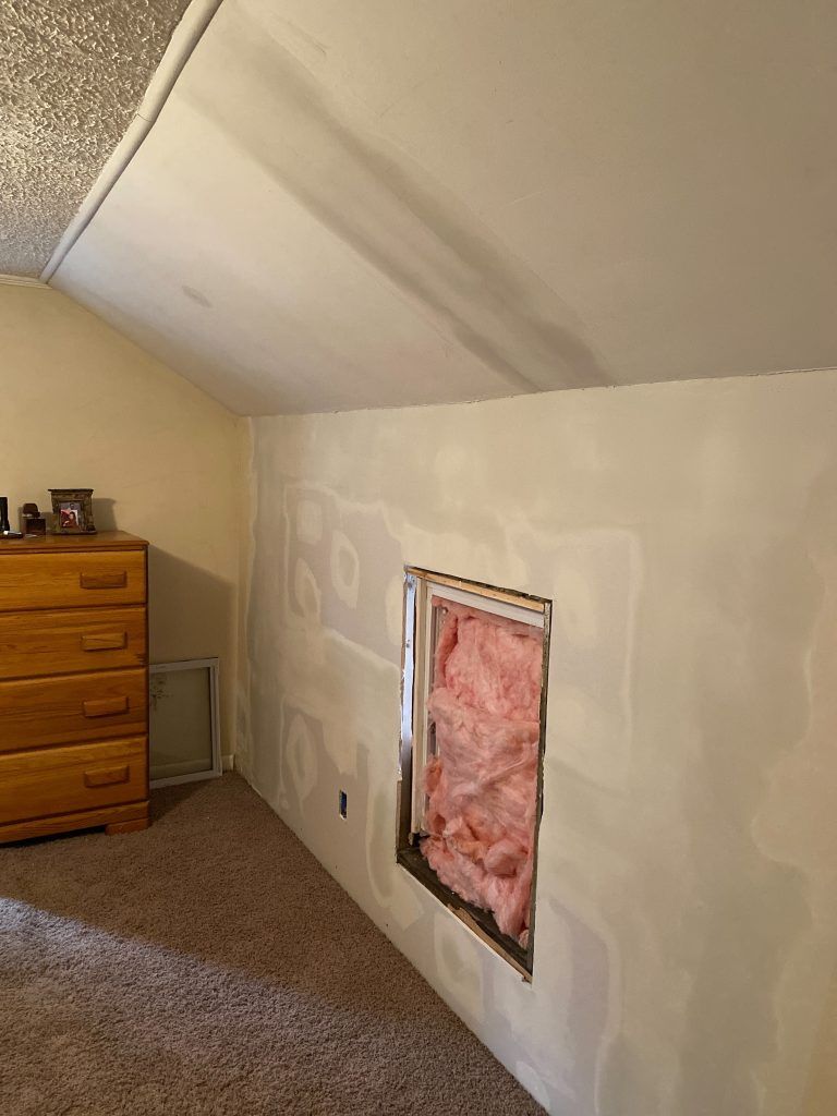 A room with a dresser and a window in the wall.