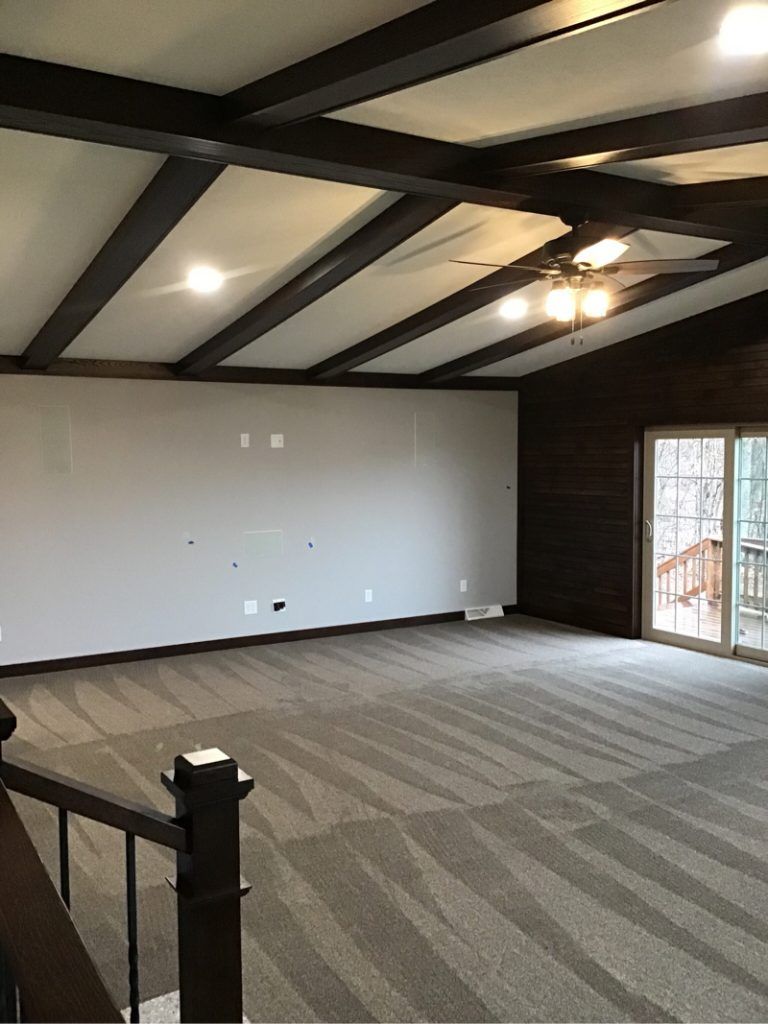 A large empty room with a ceiling fan and sliding glass doors.